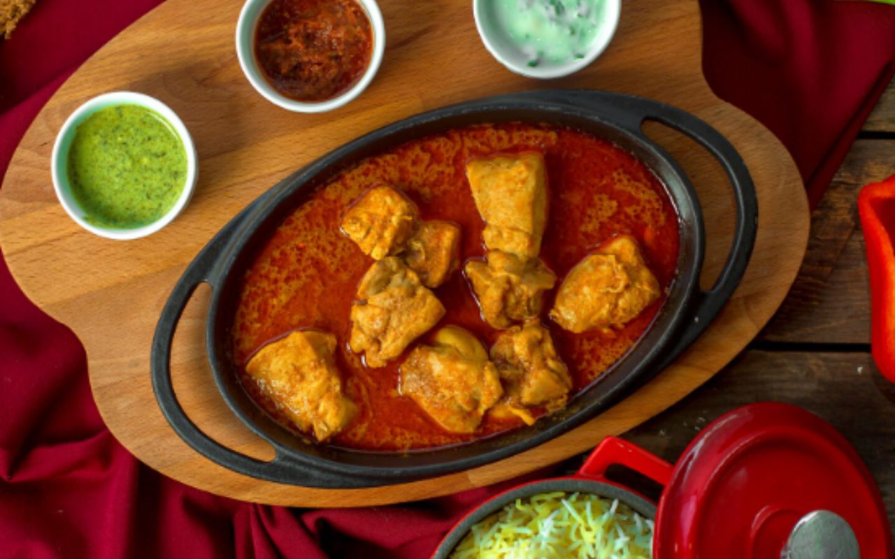 Top chiken stew with garlic in tomato sauce served with spices on wooden
