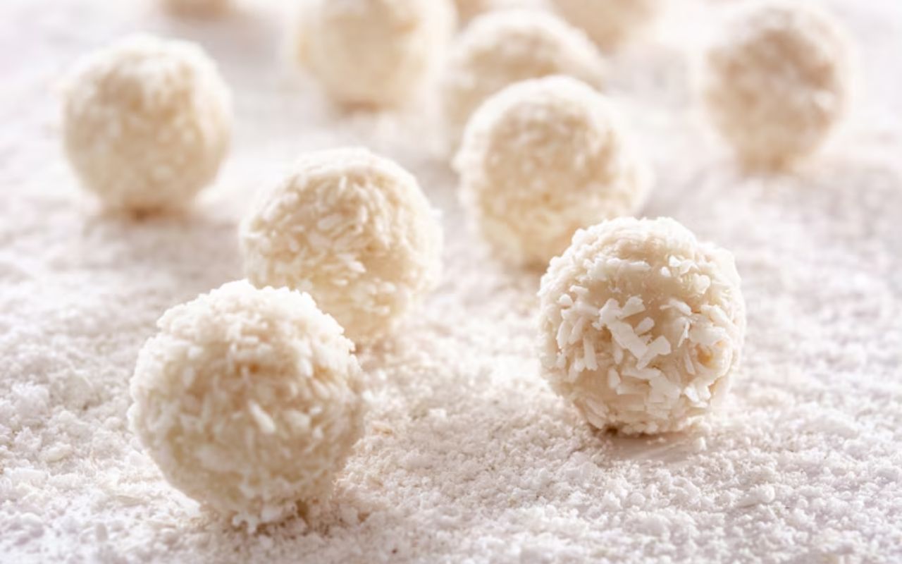 Coconut-coated snowball cookies on a white surface