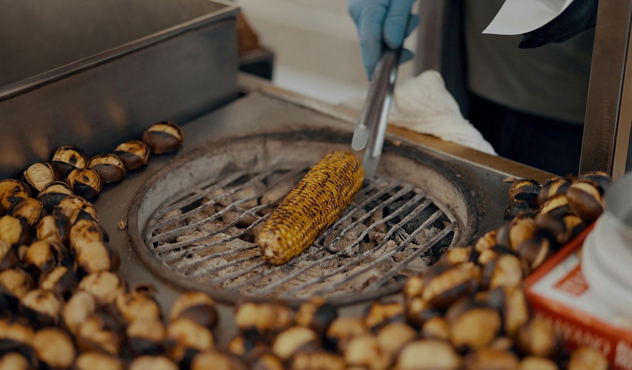 A person is cooking corn on a grill