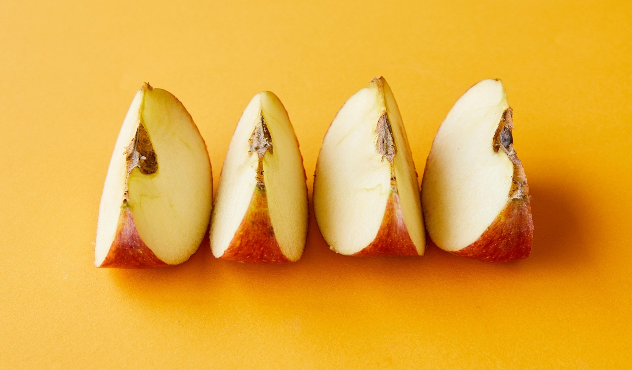 Sliced ripe red apple arranged on yellow background