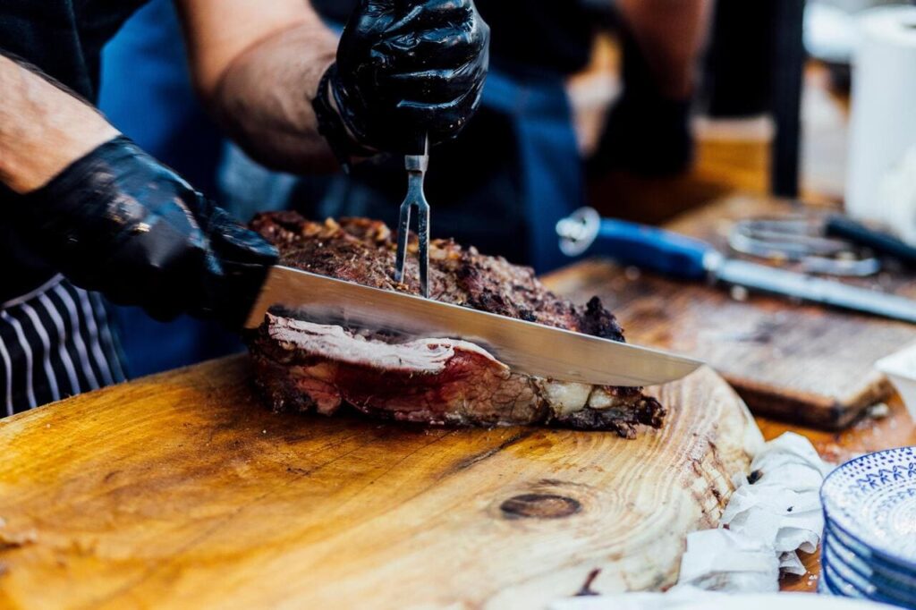 A brisket with dark, crispy bark being sliced with a large knife.
