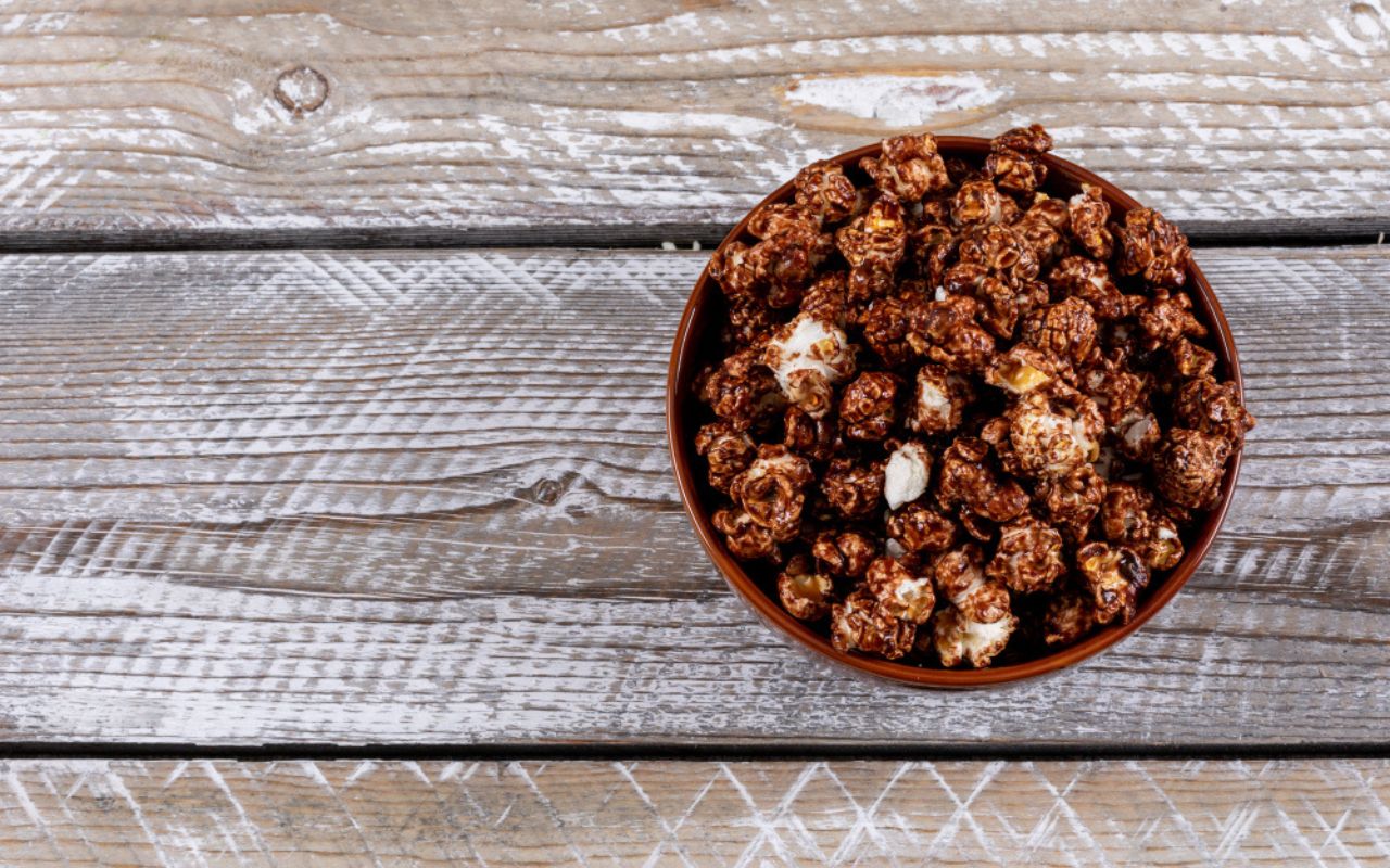 Chocolate-coated popcorn in a brown bowl on wooden table