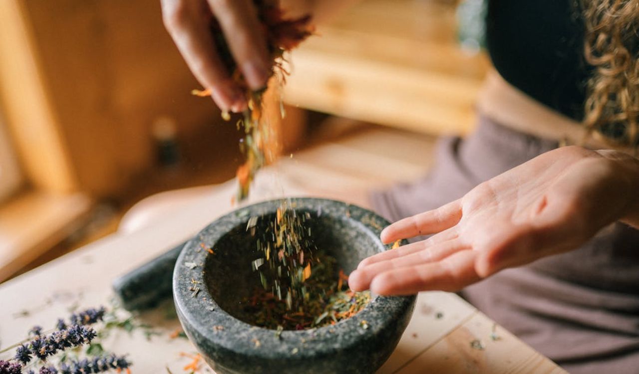 A Person Mixing Herbs by Hand in the Mortar