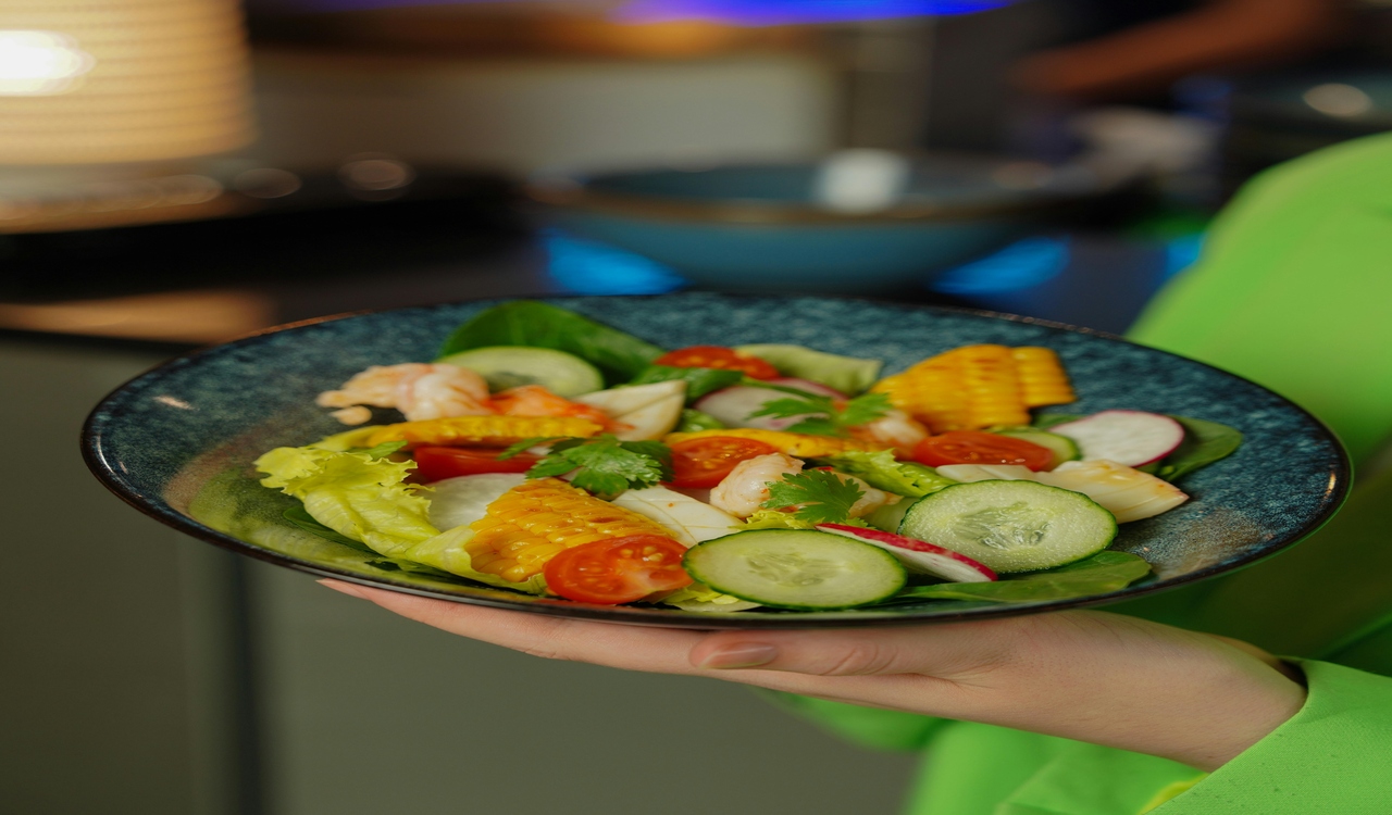 Close-up of Womans Hand Holding a Bowl With Salad With Shrimps and Corn