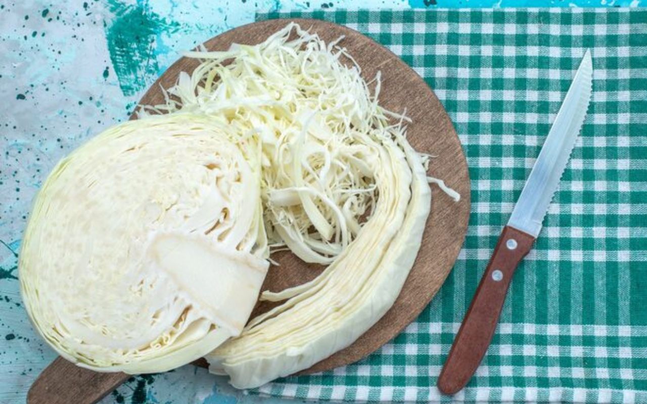 Shredded and sliced cabbage on a cutting board with a knife