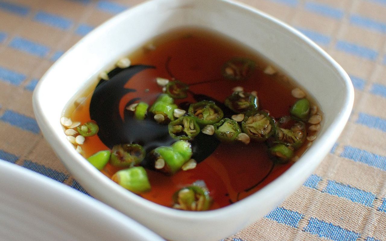 A bowl of Nuoc Mam (Vietnamese fish sauce) with sliced green chilies