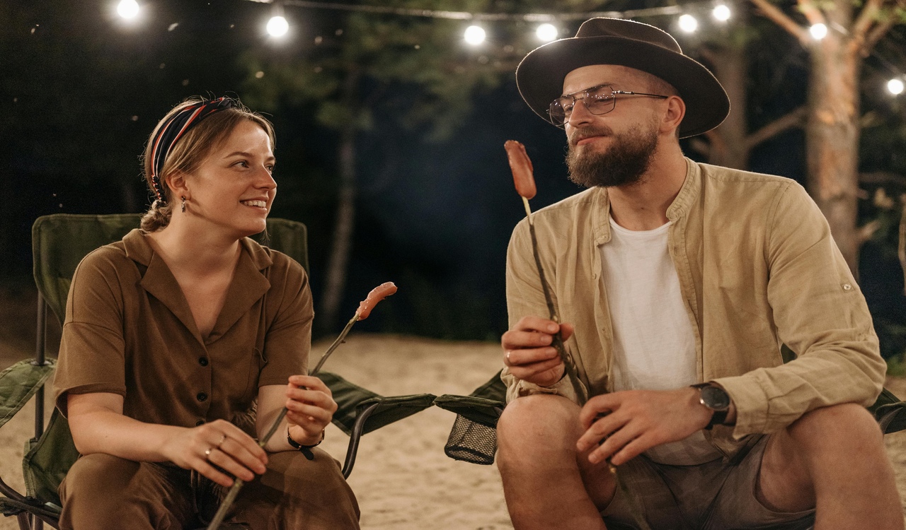 A Couple Holding a Wooden Sticks with Food while Having Conversation