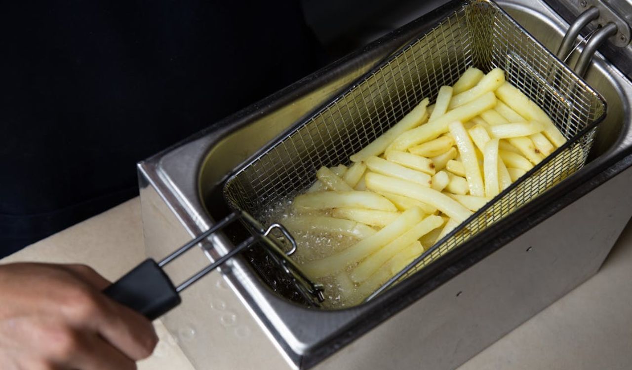 Photo of a Person's Hand Deep Frying French Fries