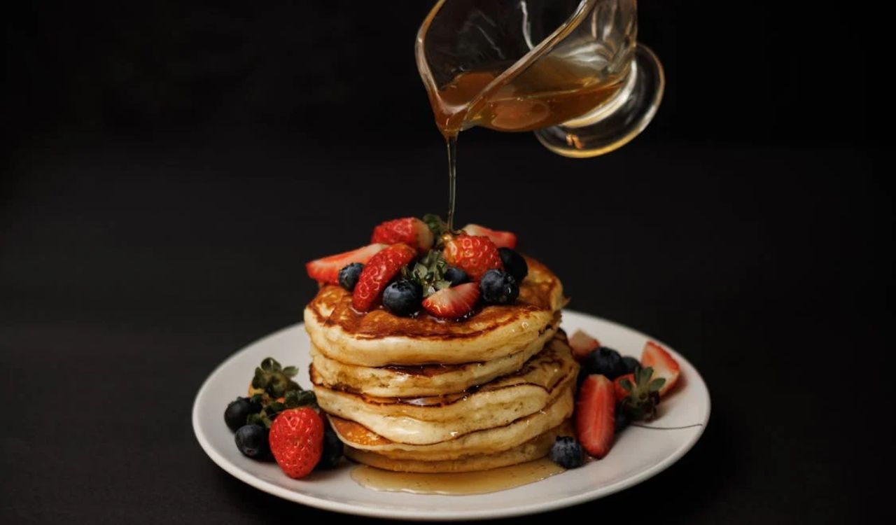 Pouring Sauce to Pancakes with Fruit