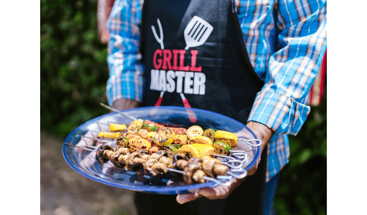 A Person in Plaid Long Sleeves and Black Apron Holding a Glass Plate with Barbecue