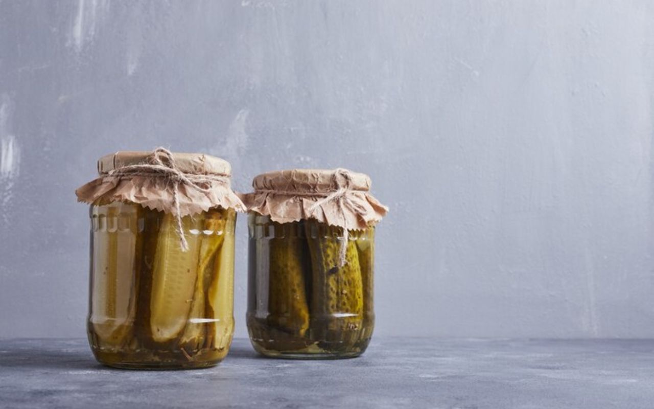Two jars of pickles with paper covers tied with string