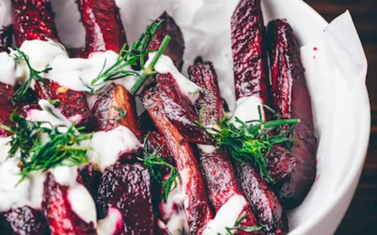 Roasted beet wedges with yogurt sauce and dill in a white bowl