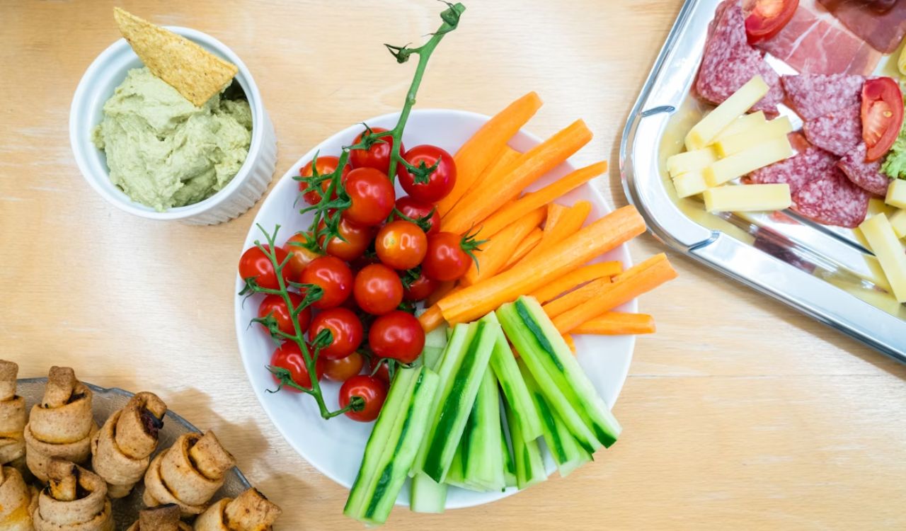 Slices of carrots zucchini and cherry tomatoes on round white ceramic bowl