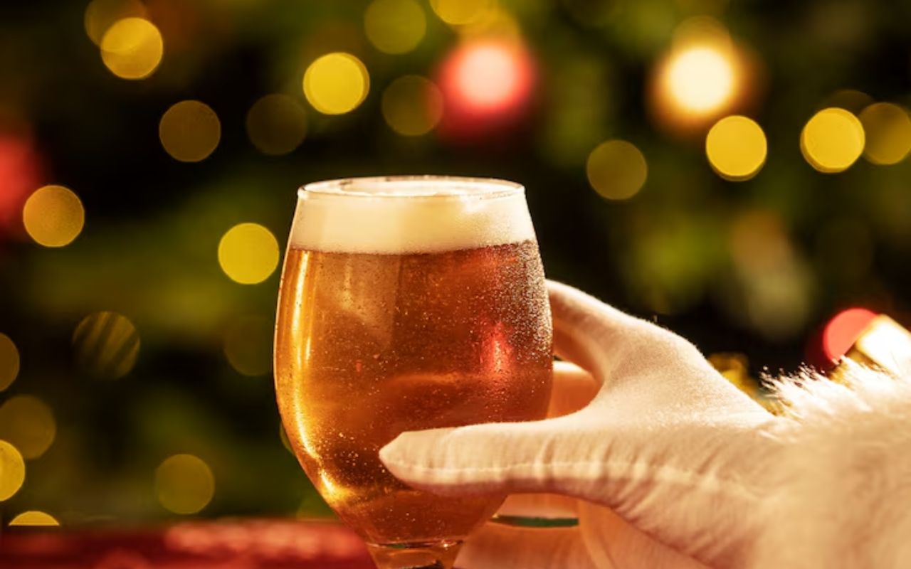 Santa’s gloved hand holding a festive beer