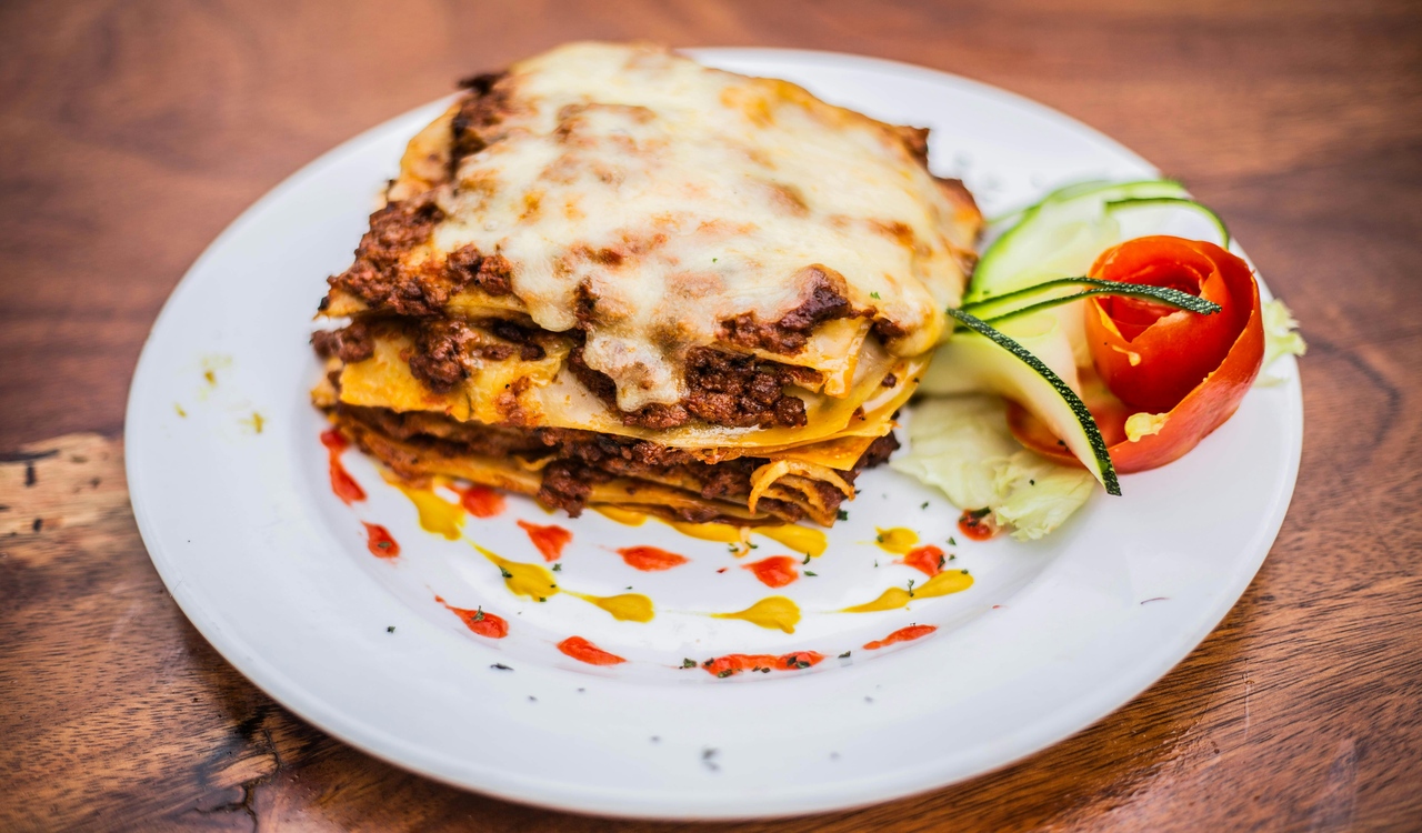 A plate topped with a lasagna and tomato sauce
