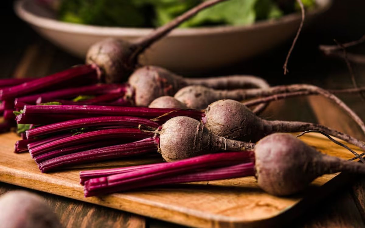 Fresh raw beets with stems on a wooden board