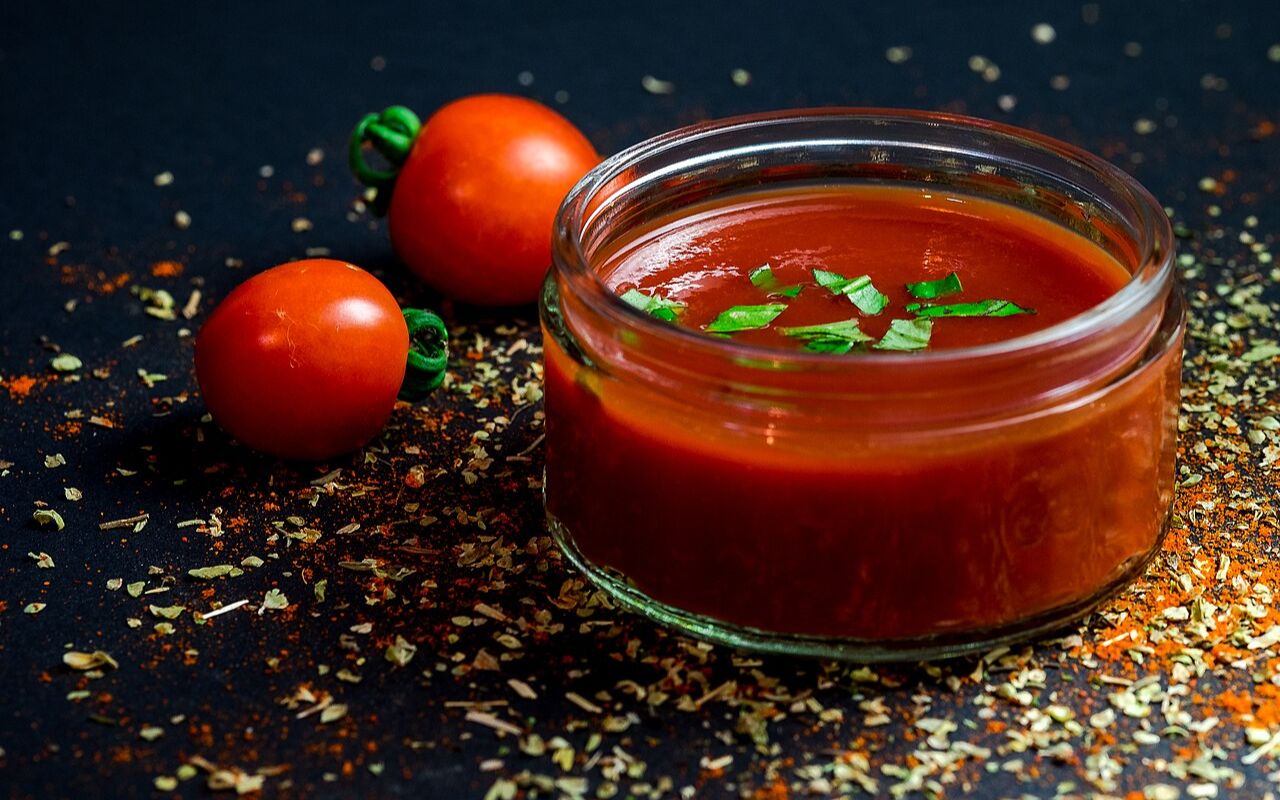 Tomato sauce in a jar with fresh herbs and tomatoes
