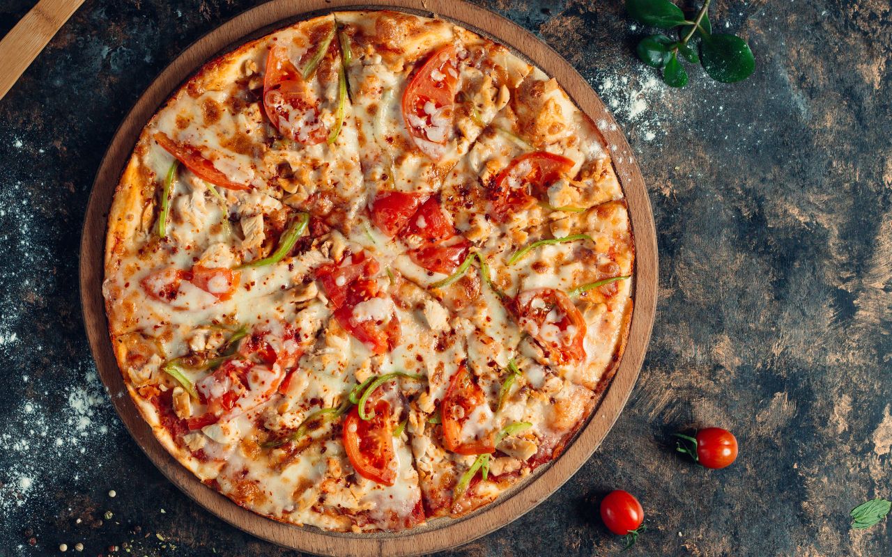 Whole pizza with tomato and pepper toppings on a board