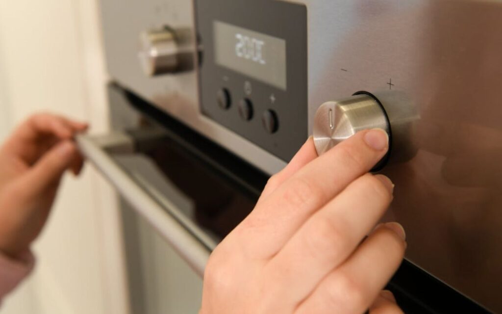 Hand adjusting oven temperature knob