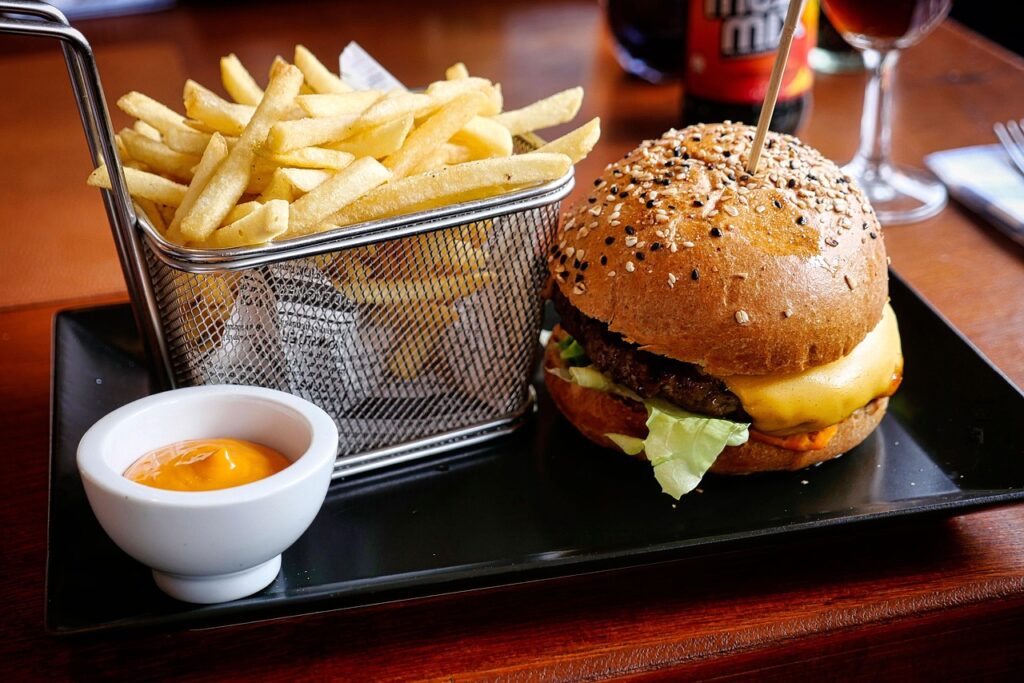 Burger with overflowing bag of fries.
