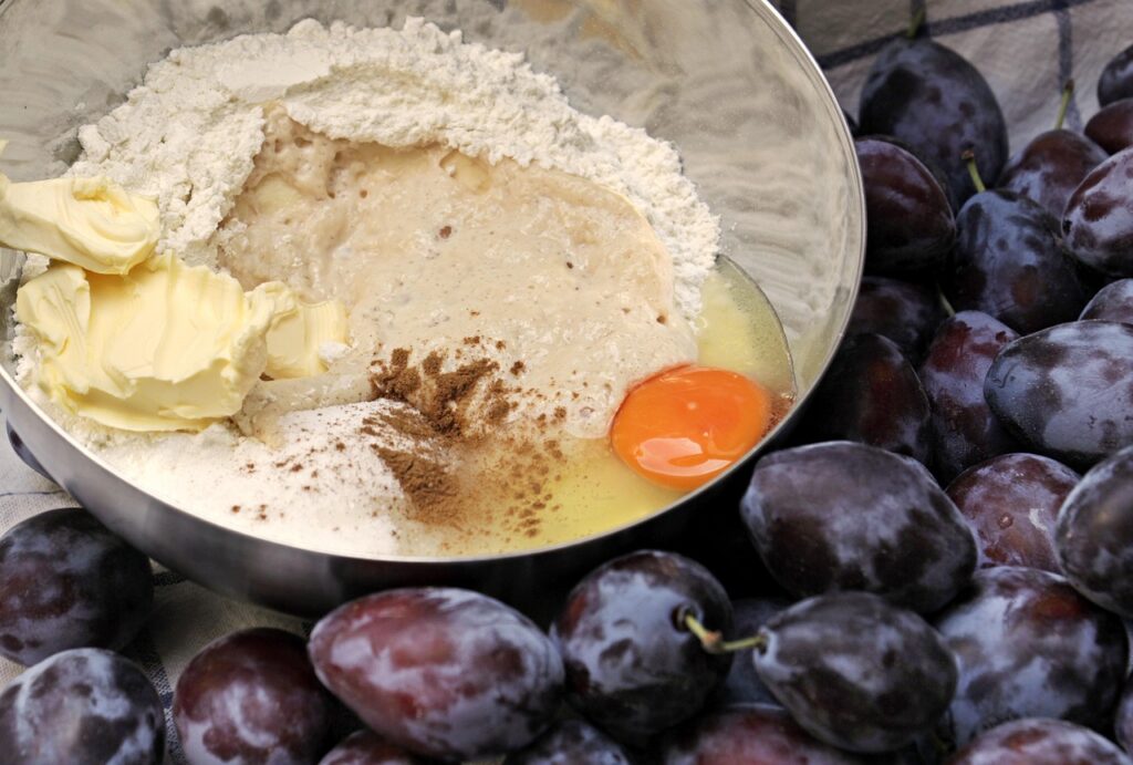 A small bowl with melted butter being poured into brownie batter.