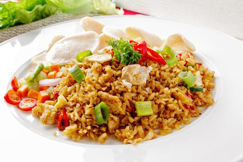 Chicken fried rice in a wok with colorful vegetables.
