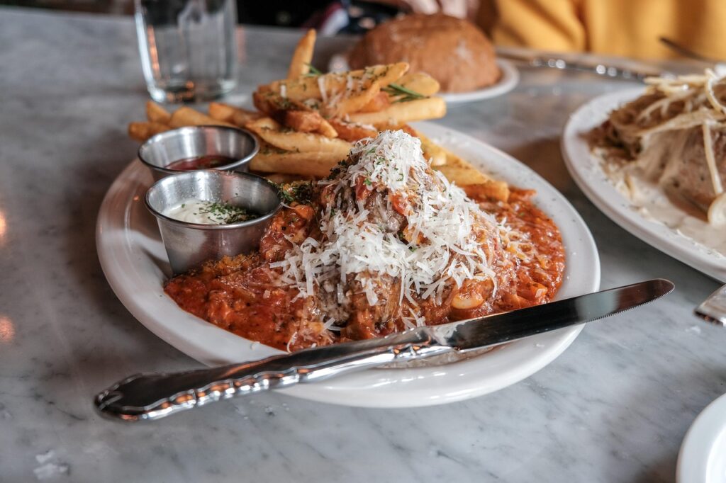 Open can of spaghetti and meatballs being poured into a bowl.