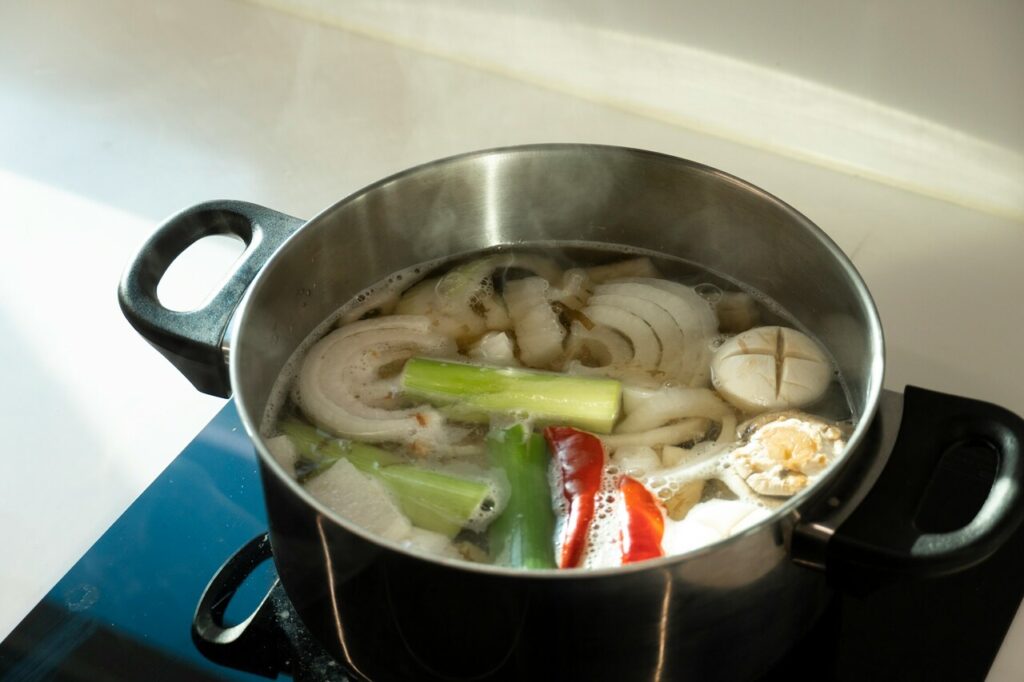 Broth simmering on stove with garlic and green onions.