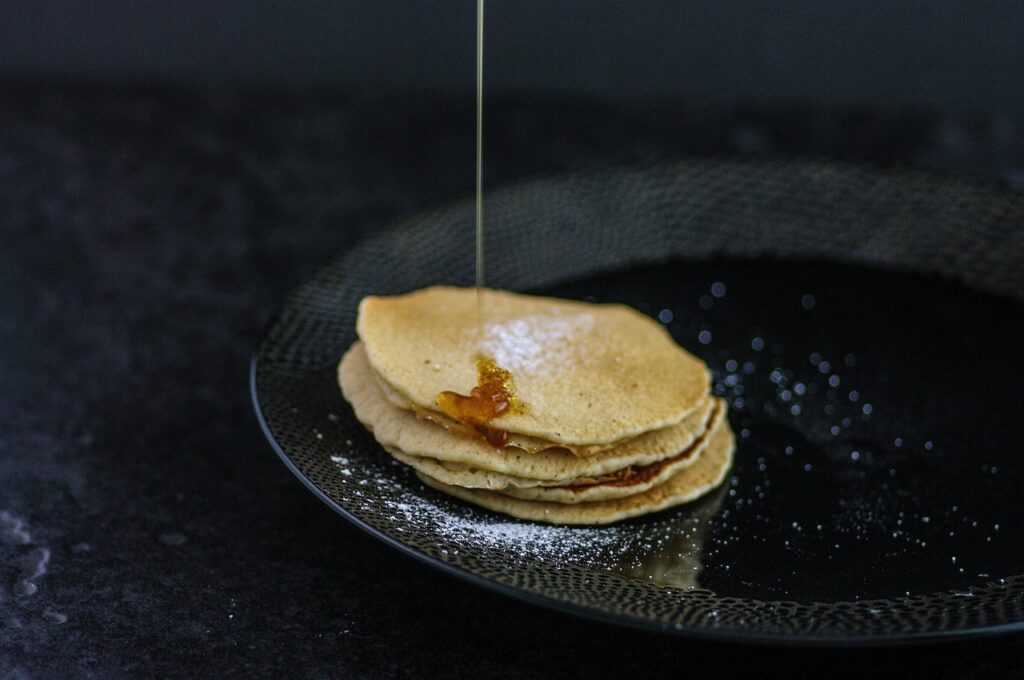 A stack of buckwheat pancakes topped with butter and maple syrup.