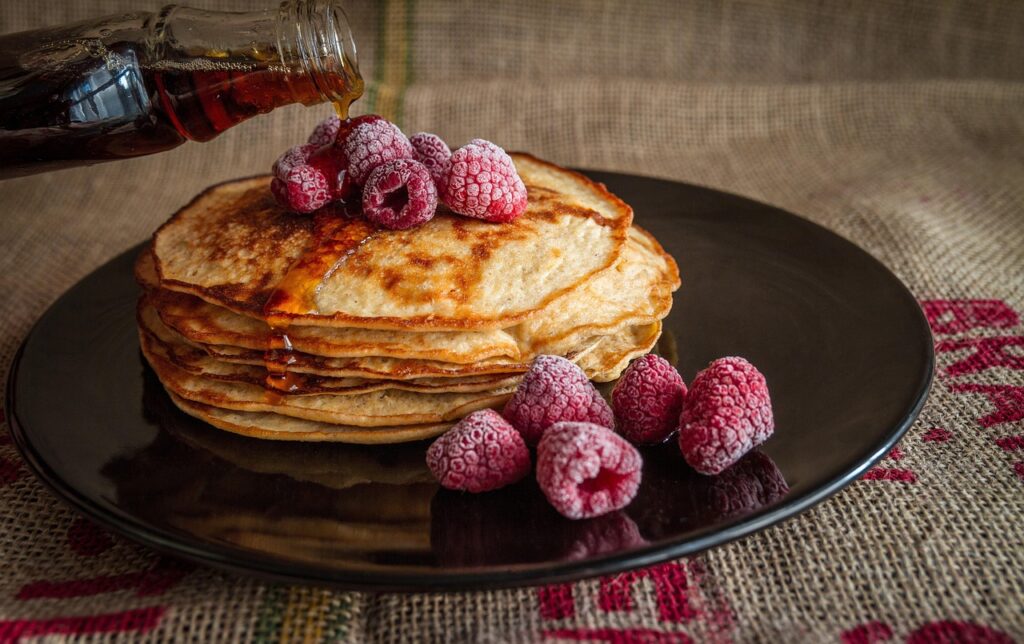 Stack of pancakes with syrup dripping down the sides.