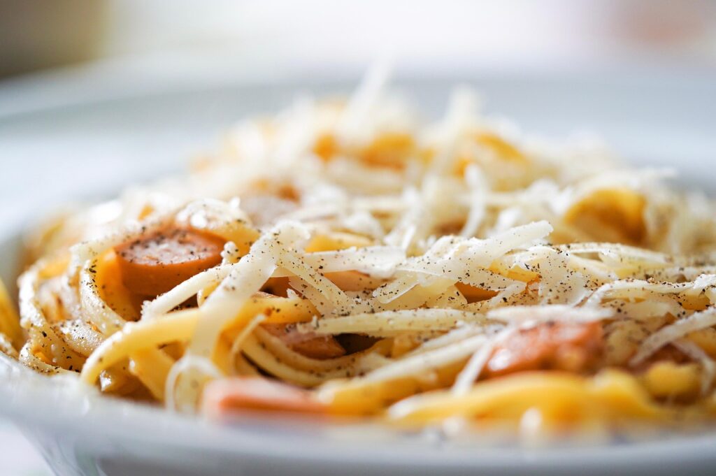 Cacio e Pepe: Close-up of pasta strands coated in creamy cheese and pepper.