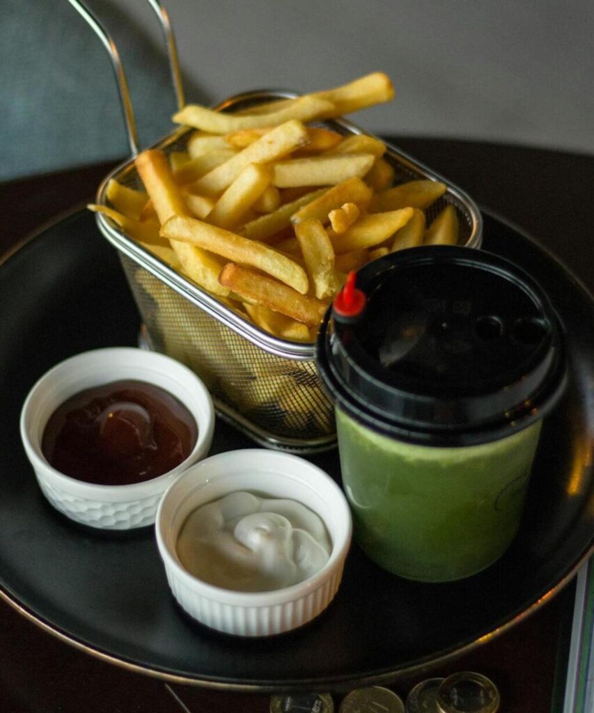 Fries being served hot on a plate ready with dipping sauces.