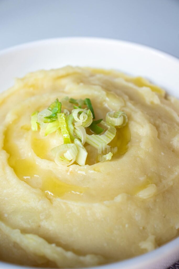 Bowl of creamy mashed potatoes with melted butter pooling in the center.