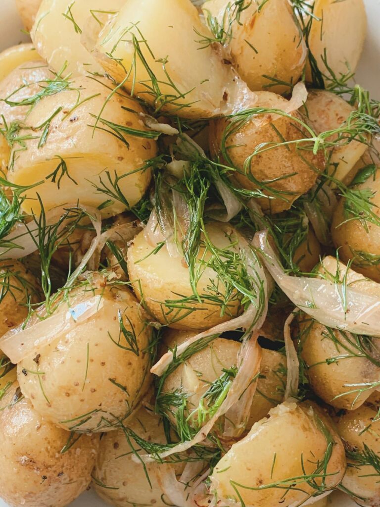 Golden mashed potato patties stacked on a plate with fresh herbs.