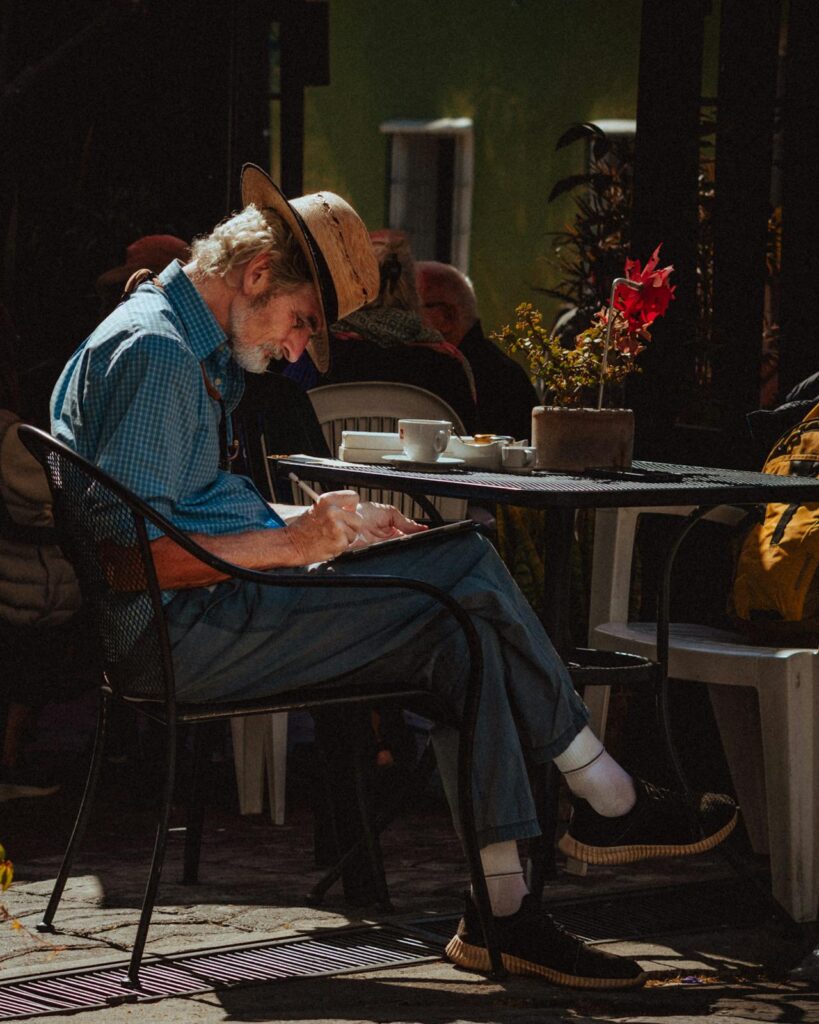 Writer sitting in a café with coffee and notebook.