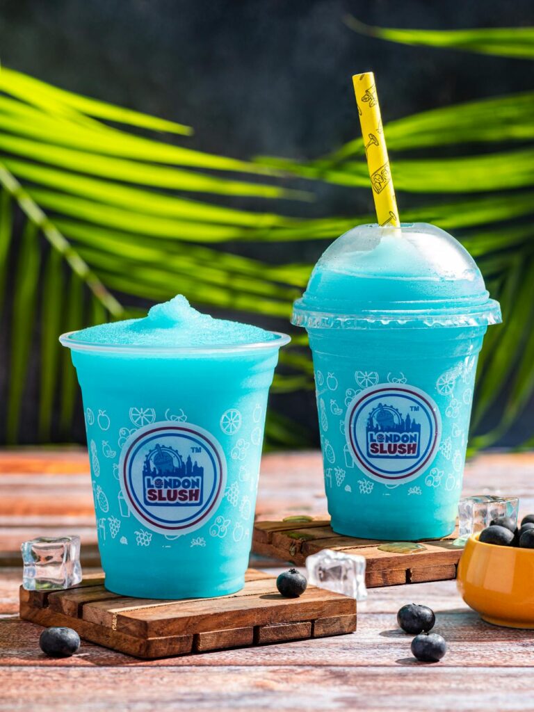 Brightly colored slush drinks in clear cups with striped straws.