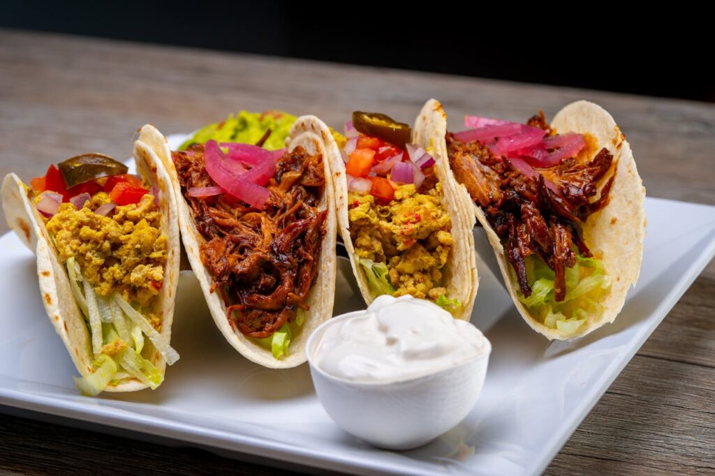 Tex-Mex Tacos: Assorted tacos with beef, eggs, and colorful toppings on soft flour tortillas.