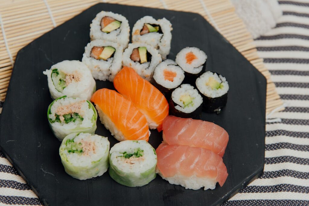 Close-up of sushi rolls on vinegared rice beside neatly arranged slices of sashimi.