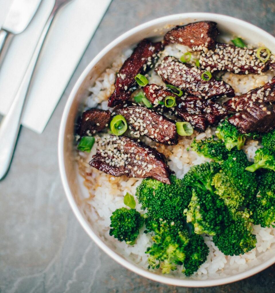 Bright, saucy beef and broccoli served over steamed rice with chopsticks.