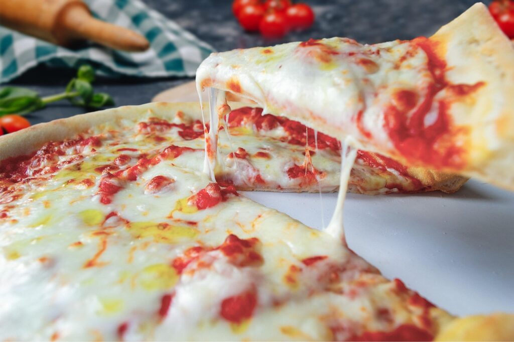 A wood-fired pizza with charred crust, fresh basil leaves, melted mozzarella, and vibrant tomato sauce.