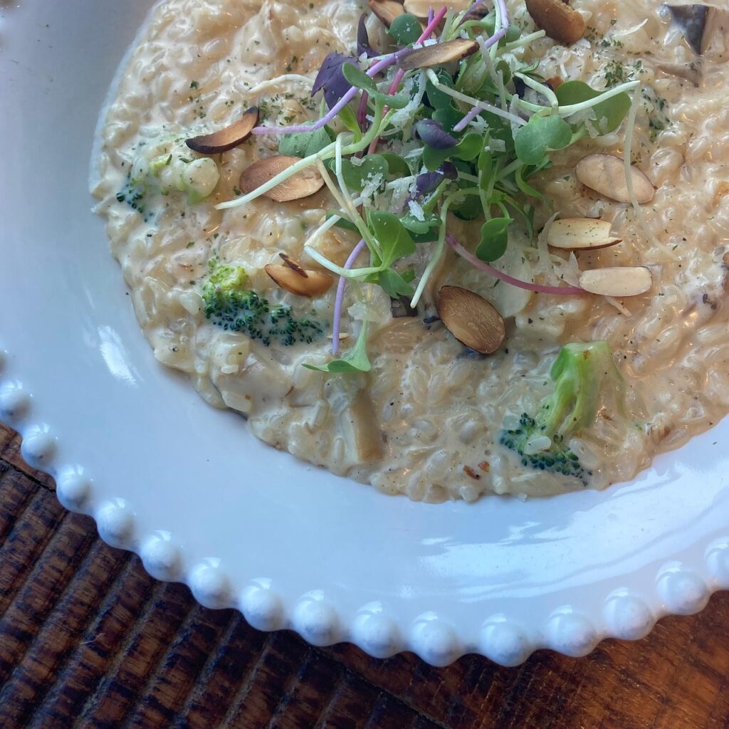 A creamy golden risotto in a shallow white bowl, garnished