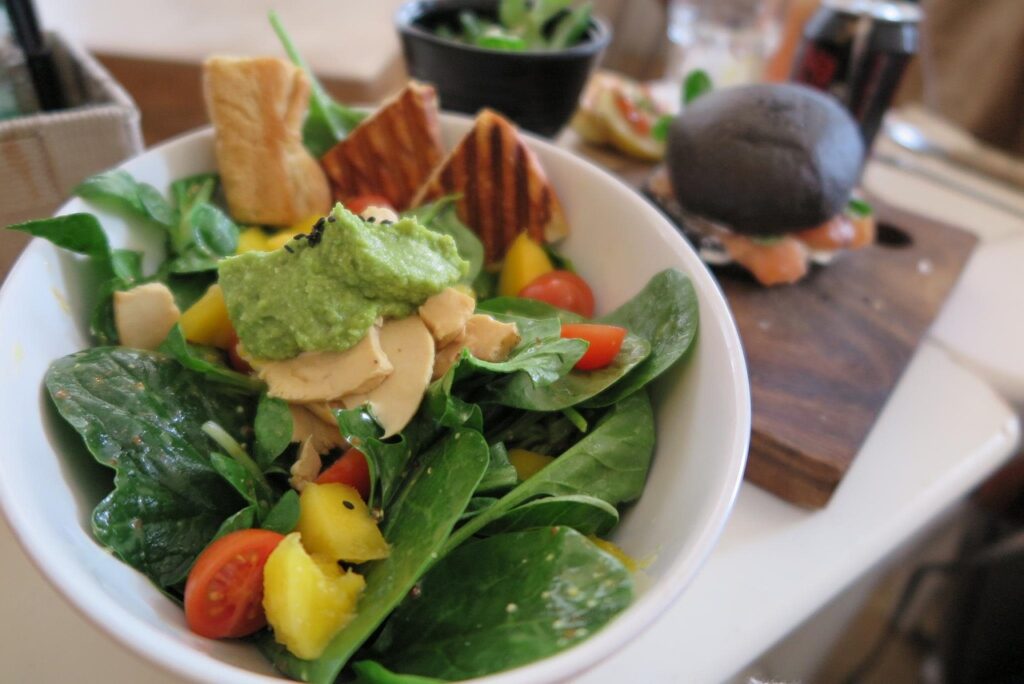 Salad bowl showing contrasting textures — creamy avocado, crunchy nuts, crisp lettuce.