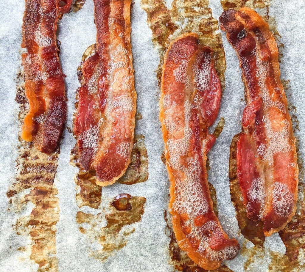 Golden, evenly crisp bacon strips cooling on plate after baking