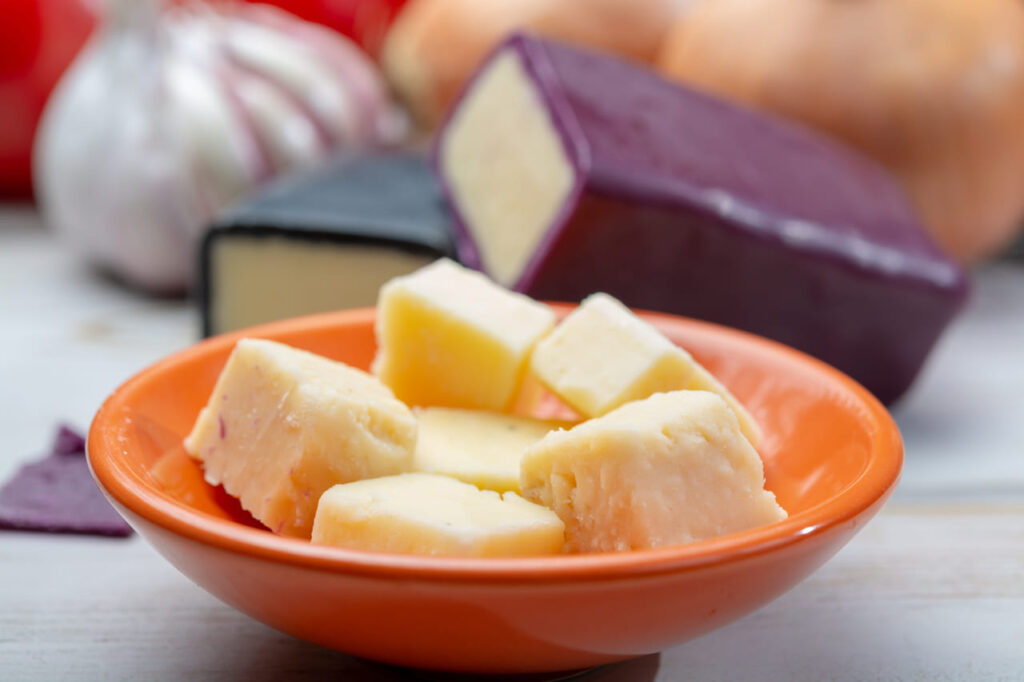 Mini black and dark red waxed cheddar cheeses with strong flavor made from West Country milk and and age-old methods with onion and garlic in England close up