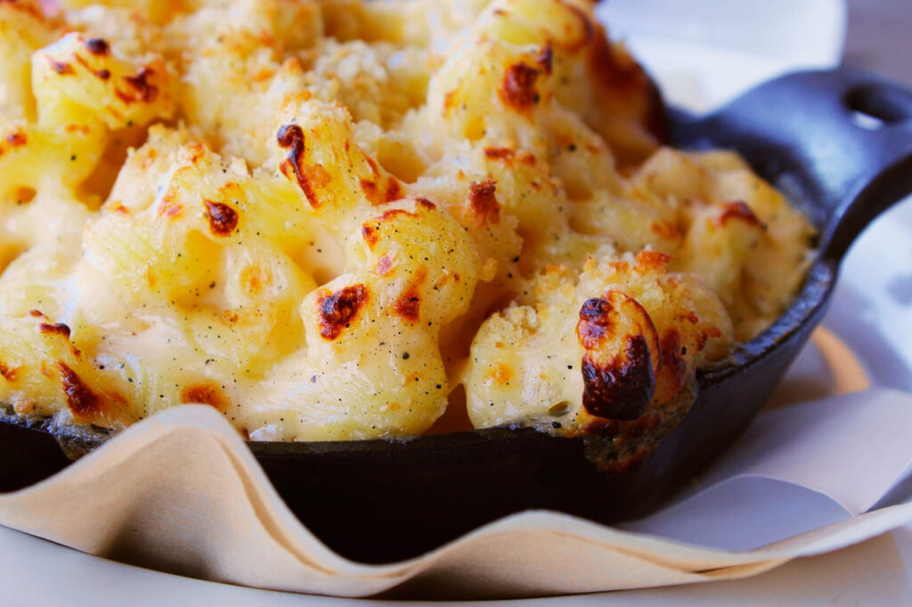 Baked mac and cheese in a cast-iron skillet with golden topping.