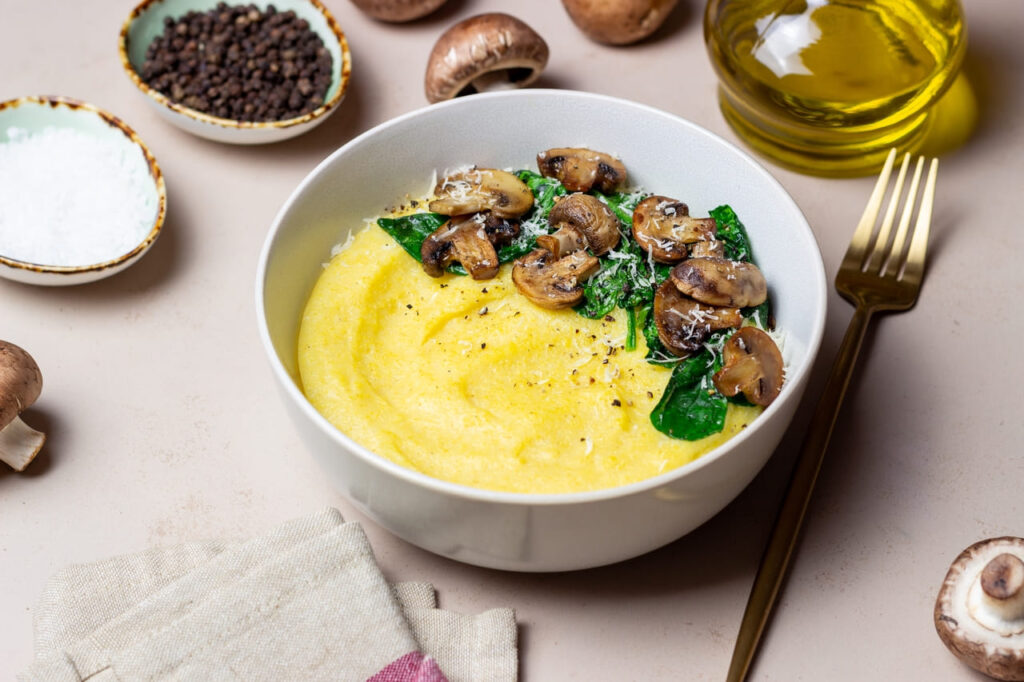 Creamy polenta in a rustic bowl, topped with sautéed mushrooms and Parmesan shavings.