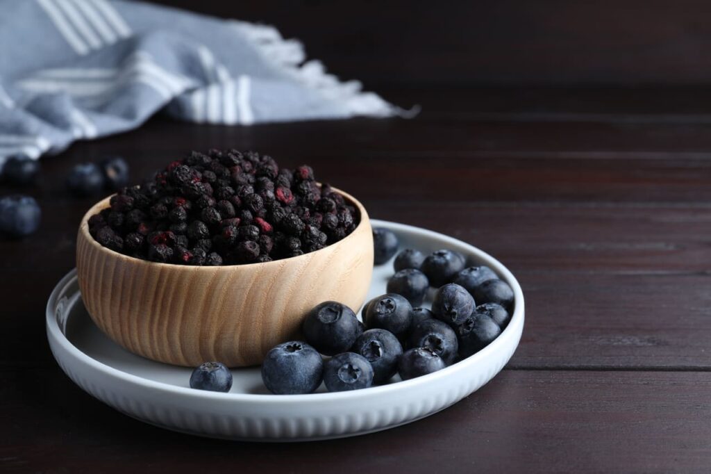 Side-by-side photo of fresh blueberries and freeze-dried blueberries.