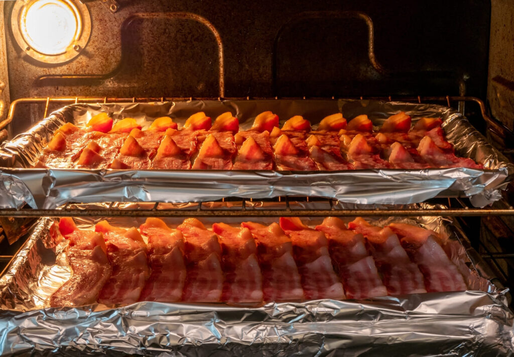 Racks of bacon baking in the oven on foil