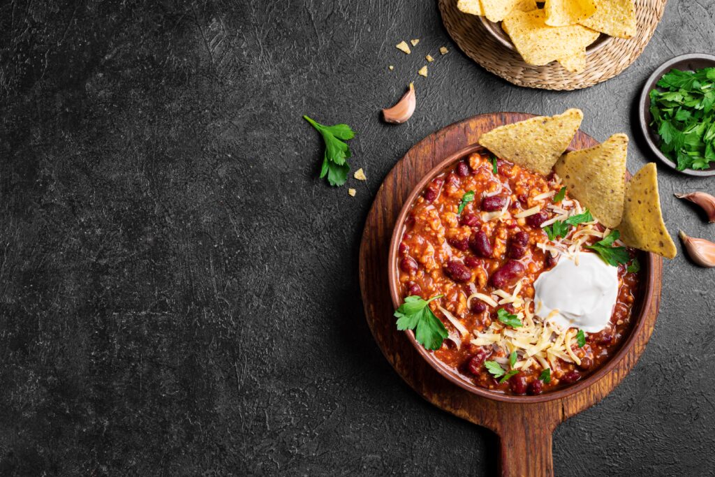 Chili,Con,Carne,With,Cheese,Topings,And,Nachos,On,Black