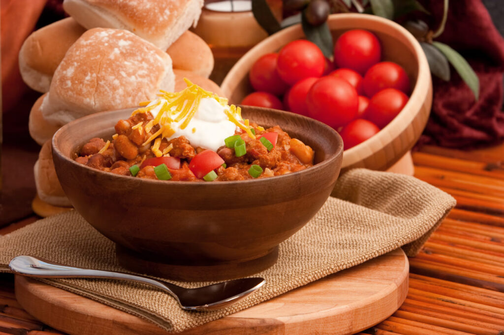 Bowl of chili topped with shredded cheese and sour cream.